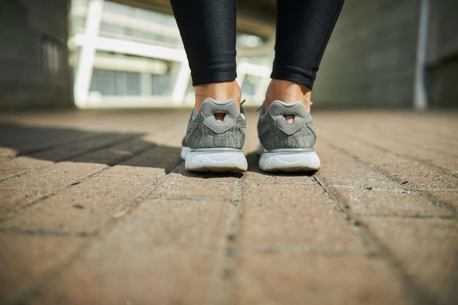 Vrouw die op tuintegels staat met sportschoenen - Hoe tuintegels schoonmaken | Asenso Schoonmaakdiensten