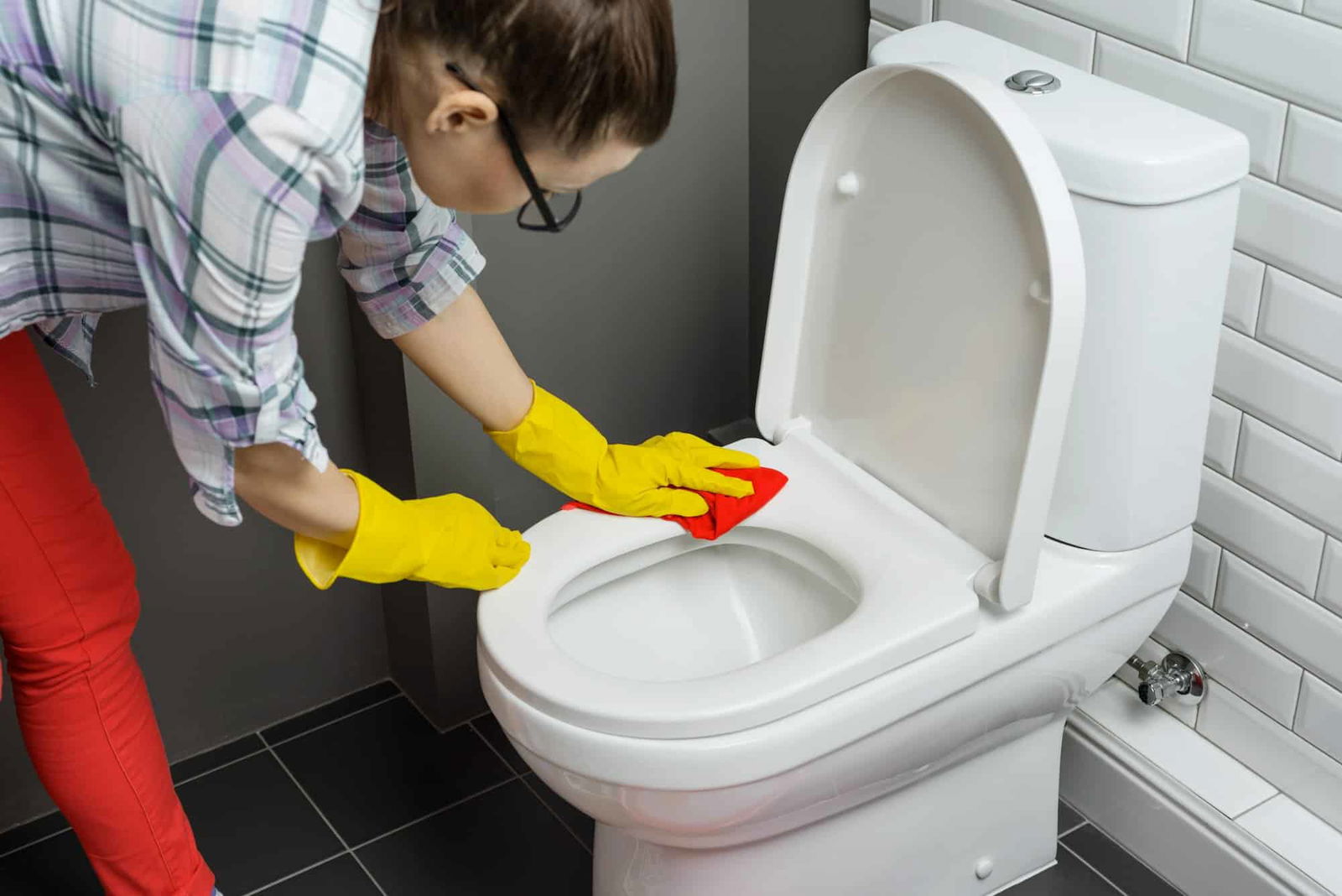 Vrouw met handschoenen die toilet schoonmaakt - Hoe toilet schoonmaken | Asenso Schoonmaakdiensten