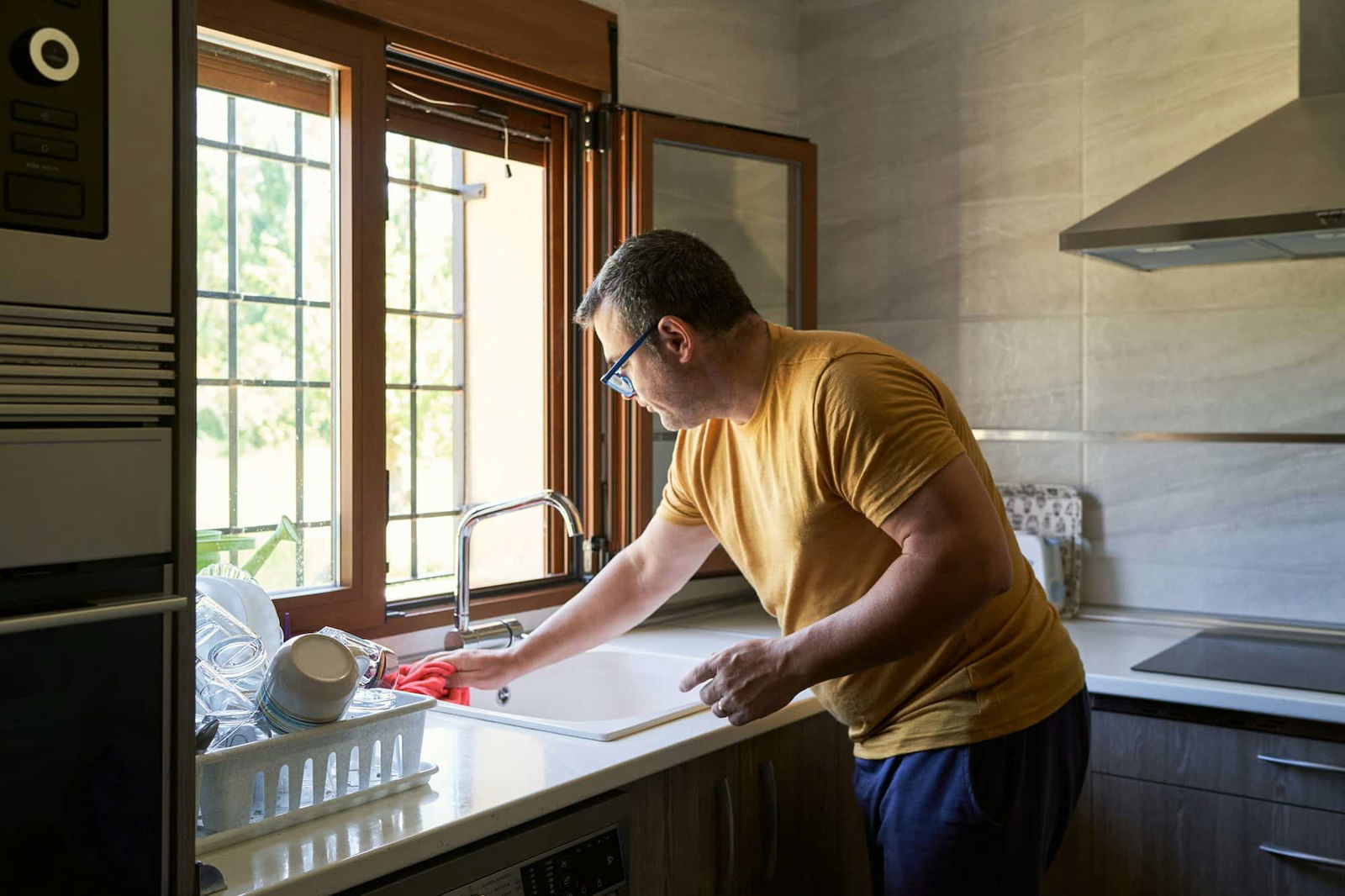 Man die gootsteen schoonmaakt met microvezeldoek - Hoe gootsteen schoonmaken | Asenso Schoonmaakdiensten