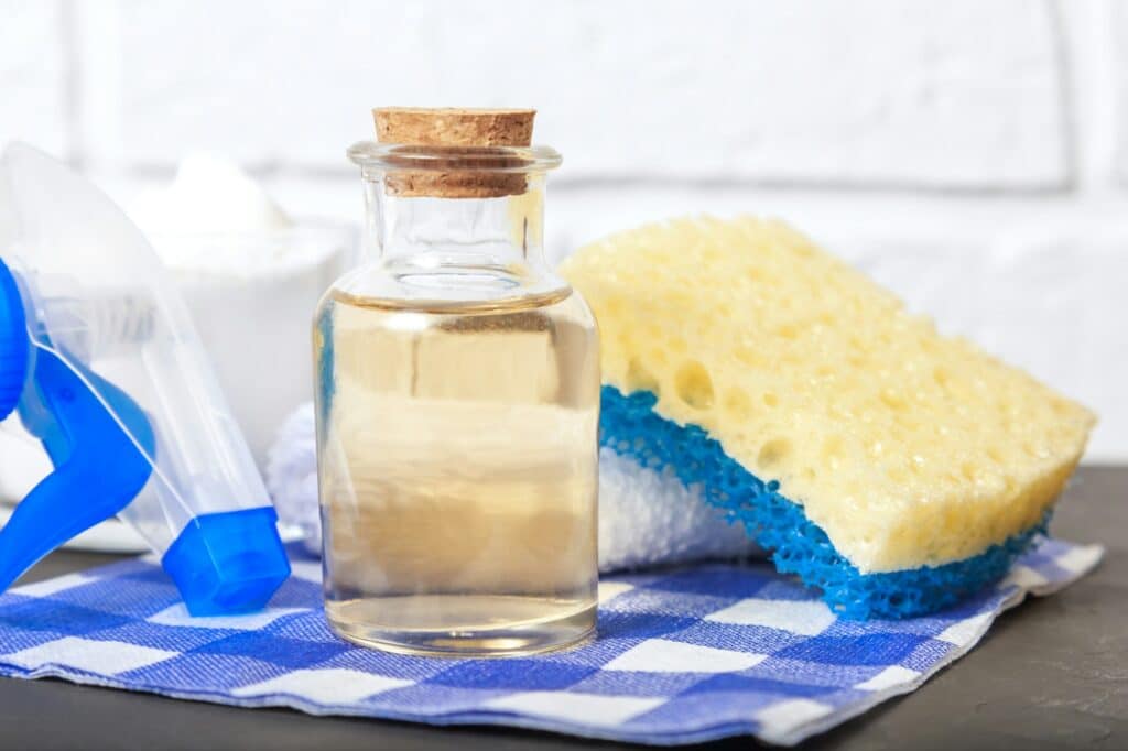 Schoonmaak azijn in glazen fles met spons | Wat mag je niet schoonmaken met schoonmaakazijn | Asenso Schoonmaakdiensten