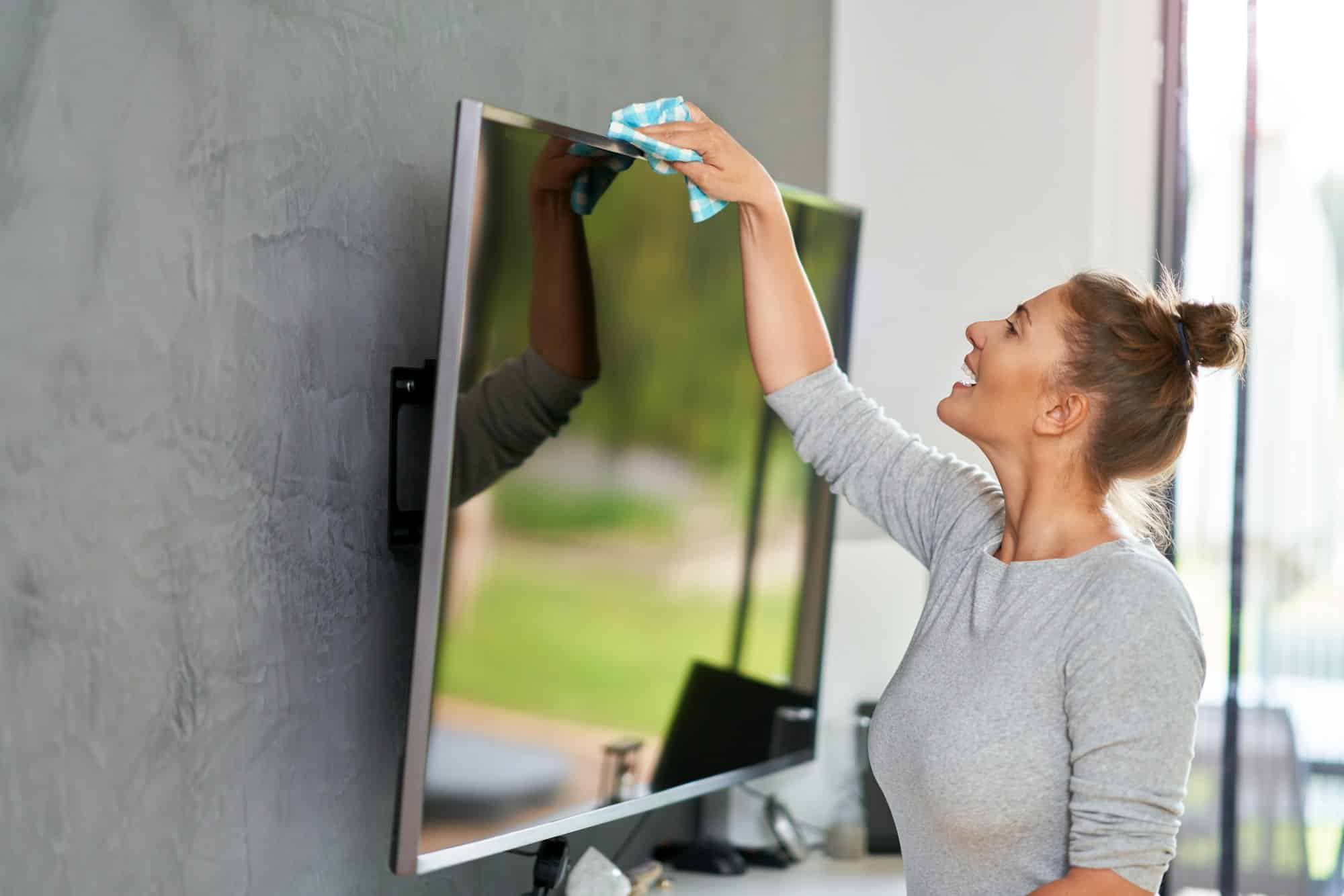 Vrouw die tv schoonmaakt | Wat mag je niet schoonmaken met schoonmaakazijn | Asenso Schoonmaakdiensten