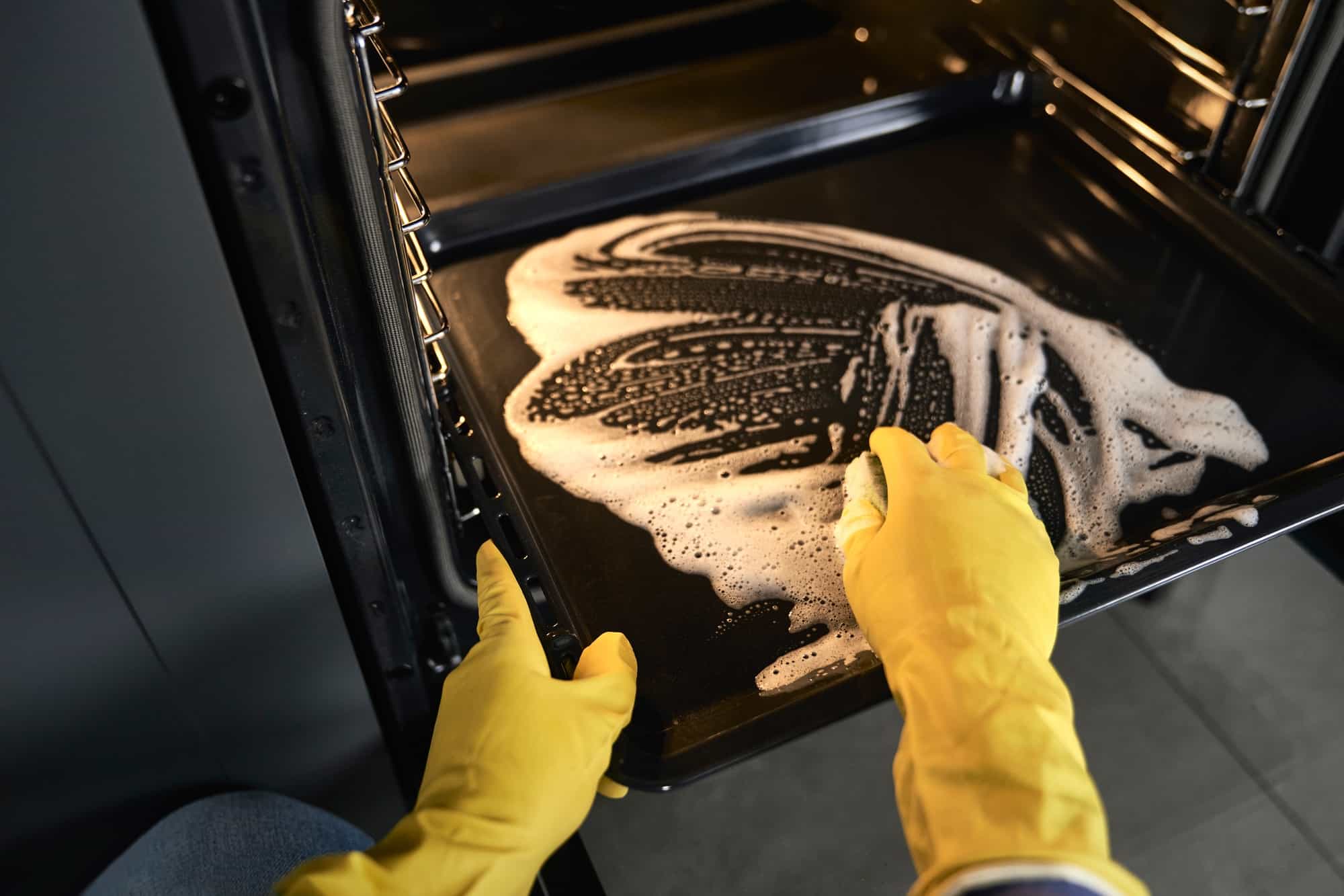 Close up van persoon die oven schoonmaakt | hoe oven schoonmaken | Asenso Schoonmaakdiensten