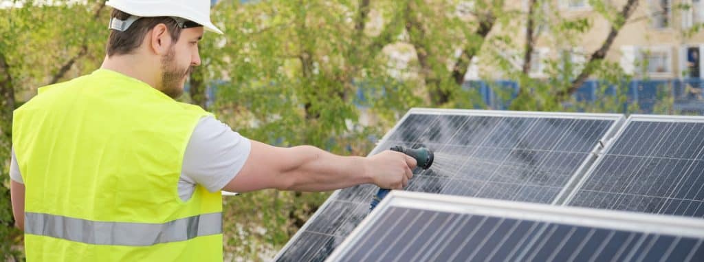 Technicus reinigt zonnepanelen met een slang | Zonnepanelen op een huis | Hoe zonnepanelen schoonmaken met tuinslang | Asenso Schoonmaakdiensten
