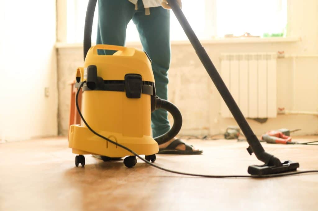 Man die kamer schoonmaakt tijdens verbouwing met behulp van een bouwstofzuiger | Hoe huis schoonmaken na verbouwing | Asenso Schoonmaakdiensten