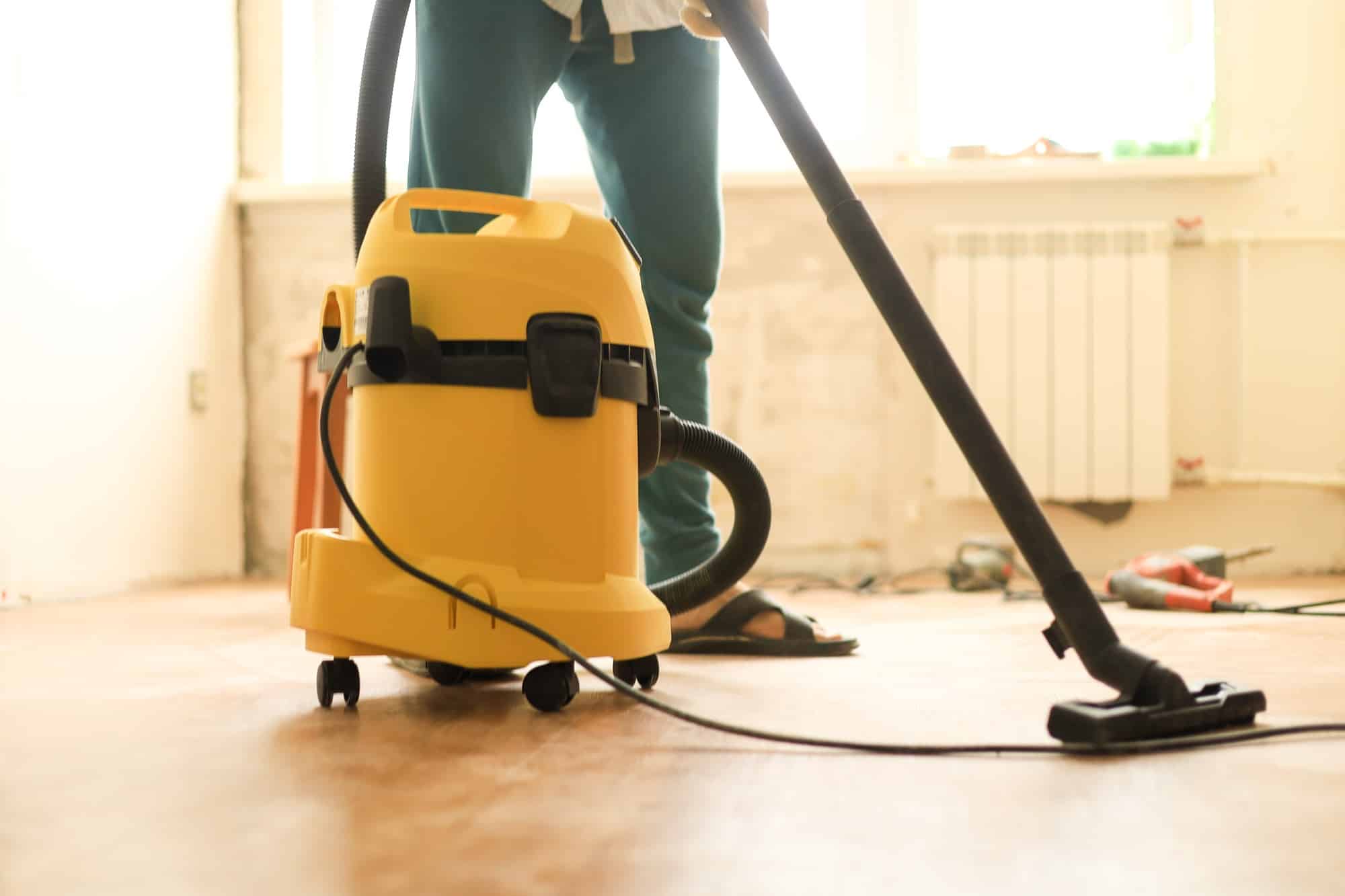 Man die kamer schoonmaakt tijdens verbouwing met behulp van een bouwstofzuiger | Hoe huis schoonmaken na verbouwing | Asenso Schoonmaakdiensten