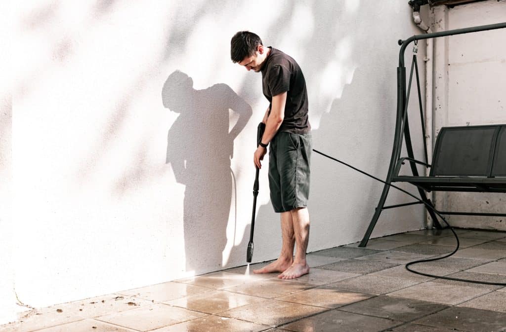 Man die tuin tegels schoonmaakt met hogedrukreiniger | groene aanslag reiniger | Asenso Schoonmaakdiensten