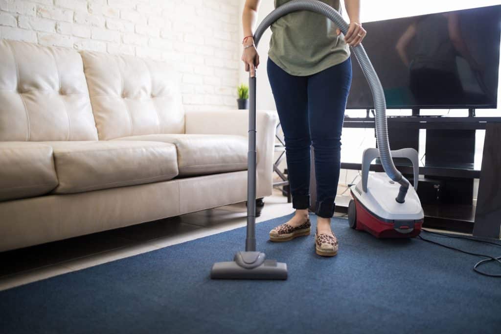 Vrouw die vloerkleed stofzuigt | Vloerkleed reinigen | Asenso Schoonmaakdiensten