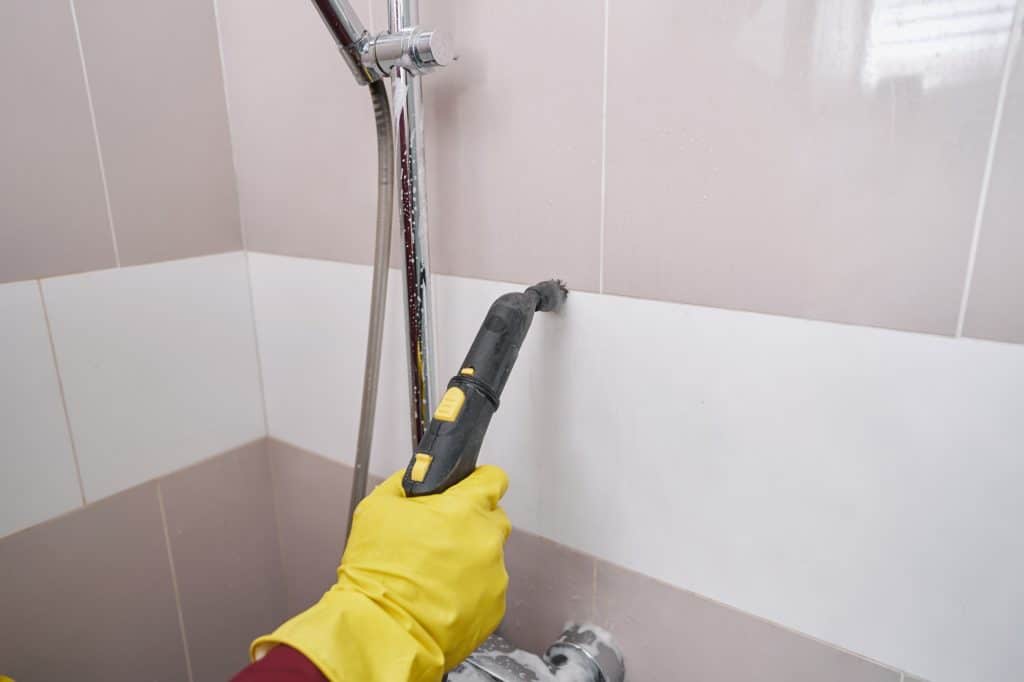 Close-up van professionele schoonmaker die voegen schoonmaakt met stoom | Badkamer voegen schoonmaken | Asenso Schoonmaakdiensten