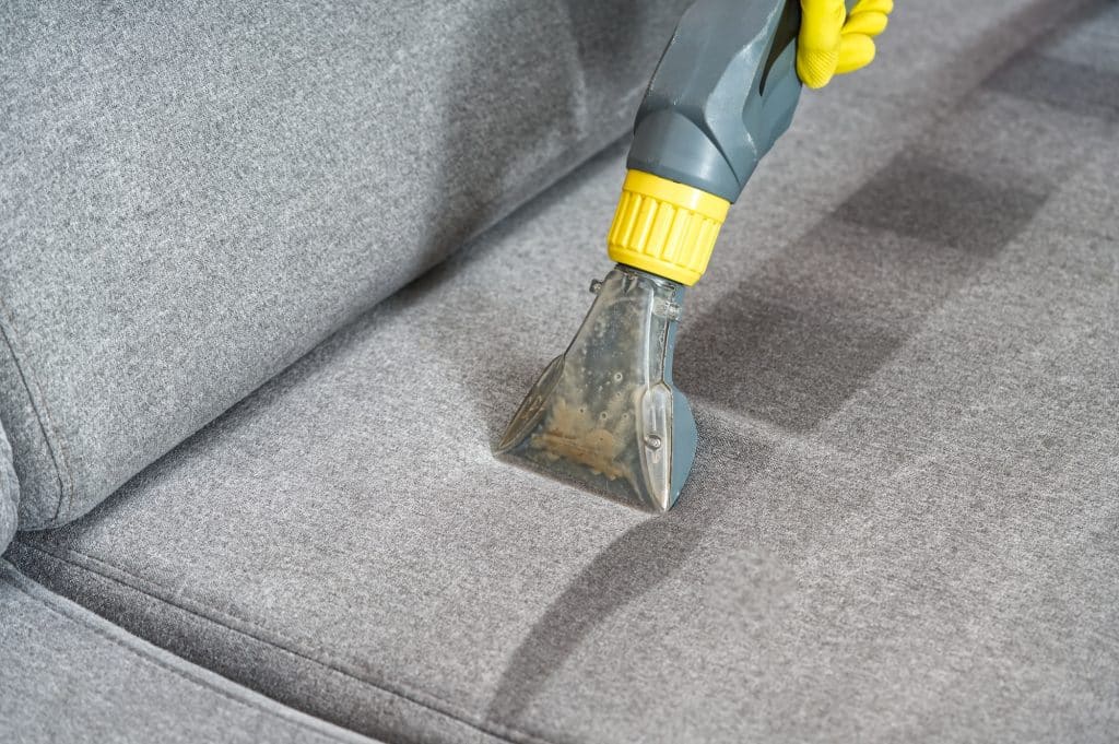 Close-up van persoon die professioneel de bank schoonmaakt | Schoonmaken allergie | Asenso Schoonmaakdiensten