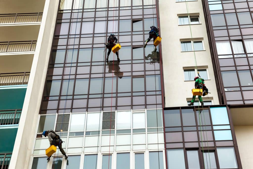 Industriële schoonmakers die gevel schoonmaken, hangend aan touwen | Gevel Schoonmaken | Asenso Schoonmaakdiensten