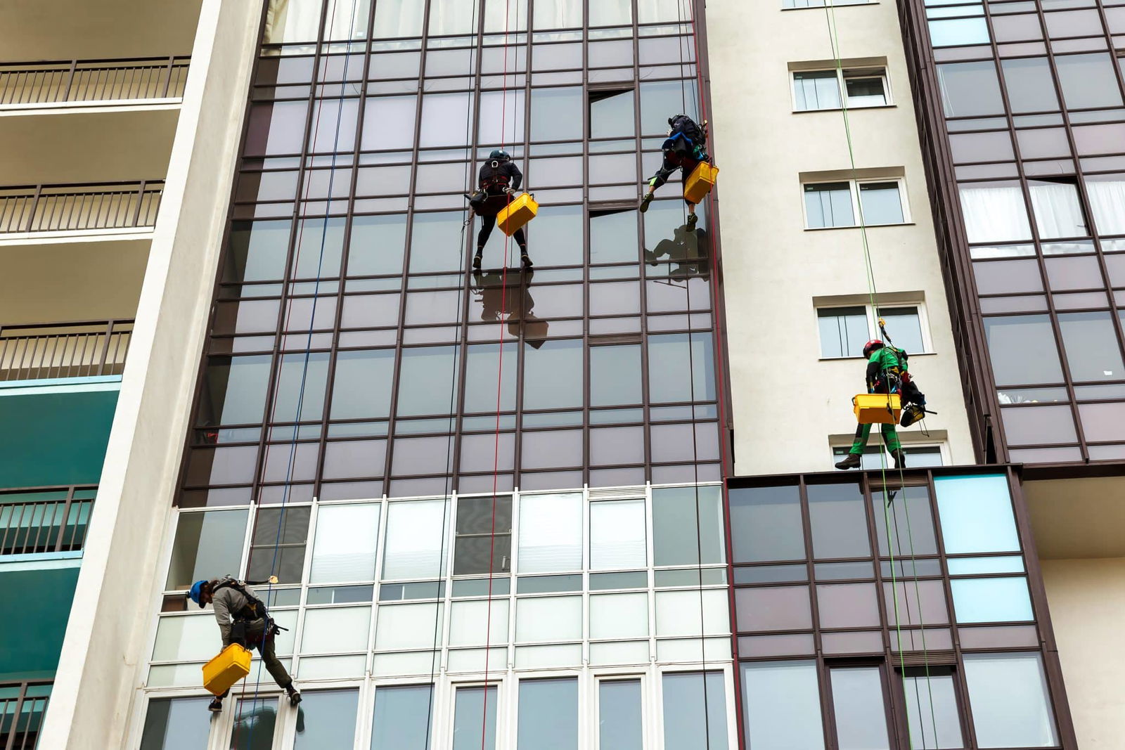 Industriële schoonmakers die gevel schoonmaken, hangend aan touwen | Gevel Schoonmaken | Asenso Schoonmaakdiensten
