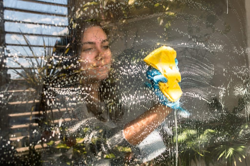 Vrouw die van binnenuit de ramen lapt | Ramen streeploos schoonmaken | Asenso Schoonmaakdiensten