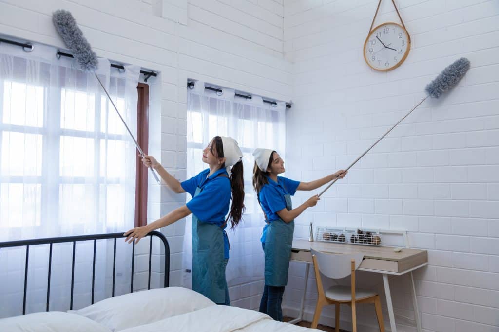 Vrouwen die het plafond schoonmaken met een plumeau | Plafond schoonmaken zonder strepen | Asenso Schoonmaakdiensten