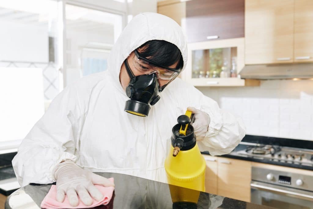 Man in hazard suit die keukenblad schoonmaakt | Calamiteiten Schoonmaak | Asenso Schoonmaakdiensten