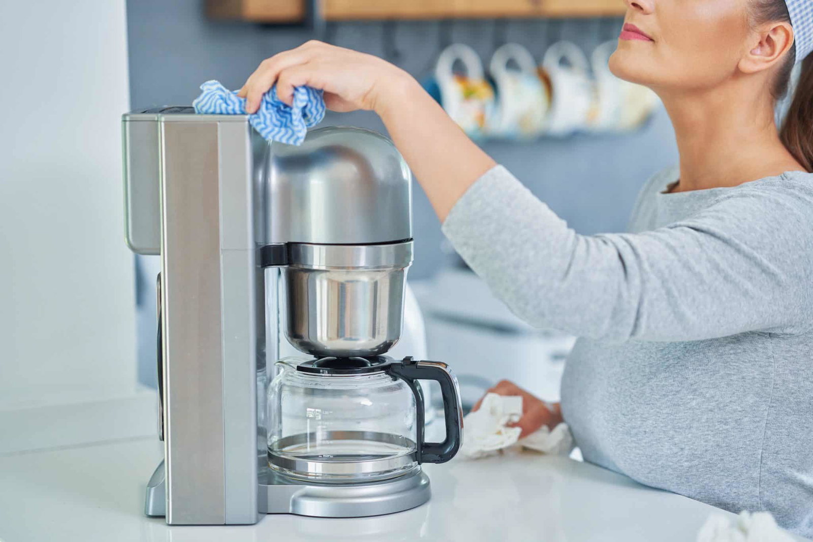 Vrouw die filterkoffieapparaat schoonmaakt | Koffiezetapparaat schoonmaken | Asenso Schoonmaakdiensten