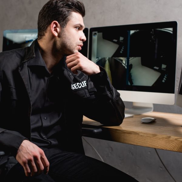 concentrated guard in uniform looking at computer monitor at workplace