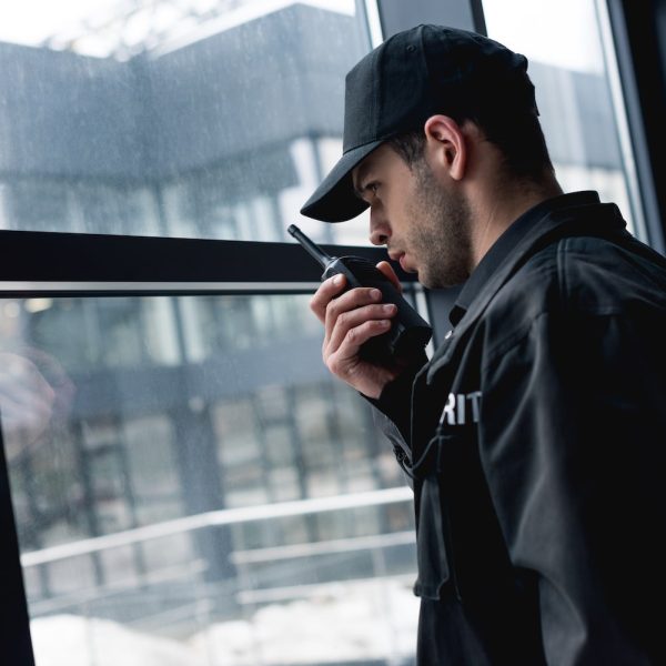 handsome guard in black uniform talking on walkie-talkie