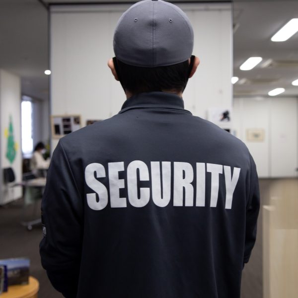 A rear view of a security guard in uniform patrolling in a commercial building