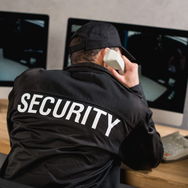 rear view of guard in uniform talking on telephone at workplace