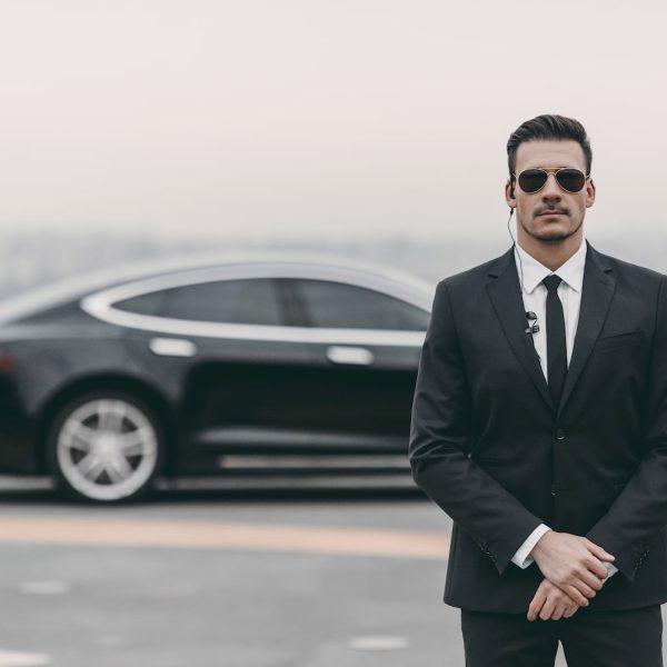 serious bodyguard standing with sunglasses and security earpiece on helipad